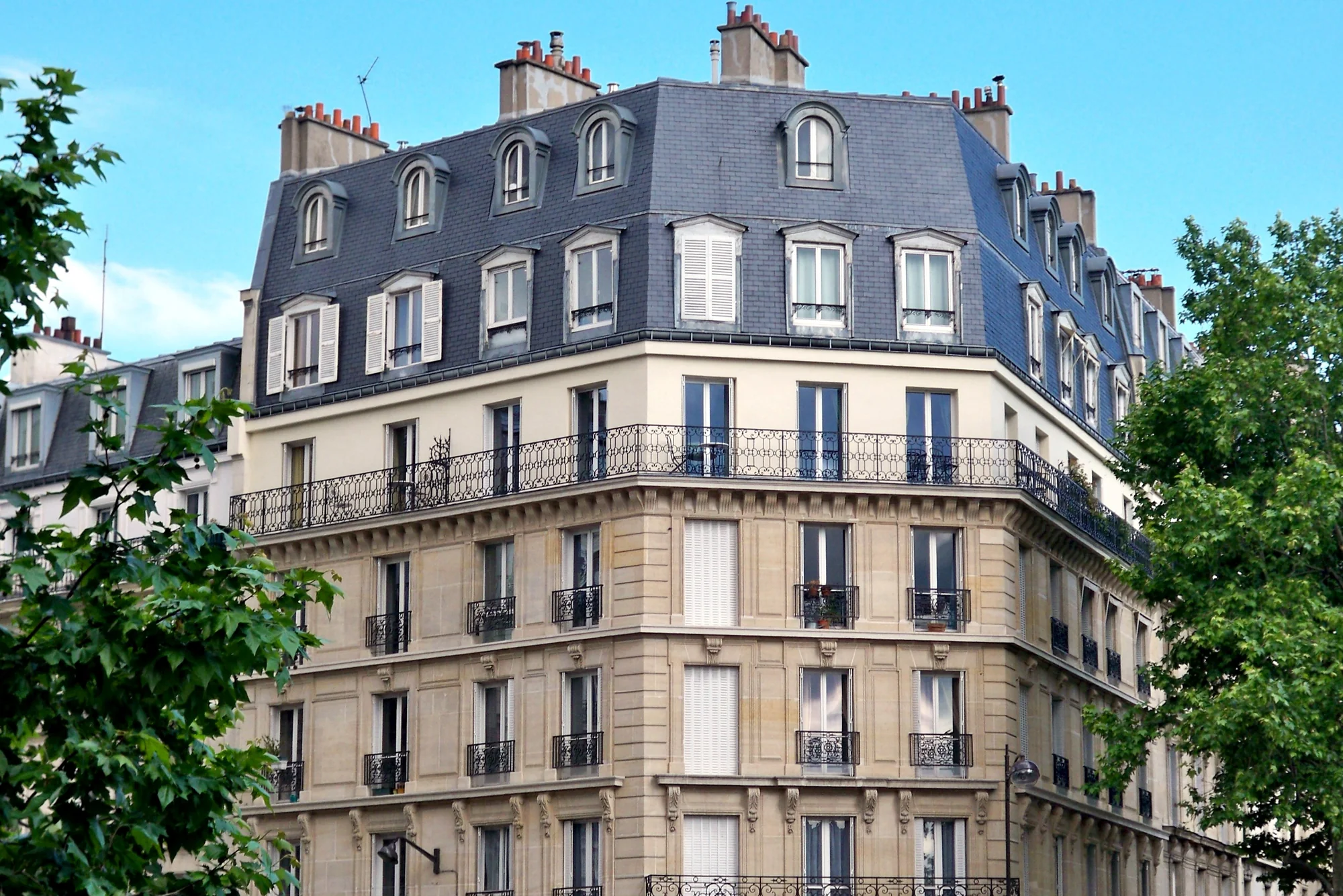 Un parent et un enfant regardent une tablette parmi des cartons, dans un appartement haussmannien